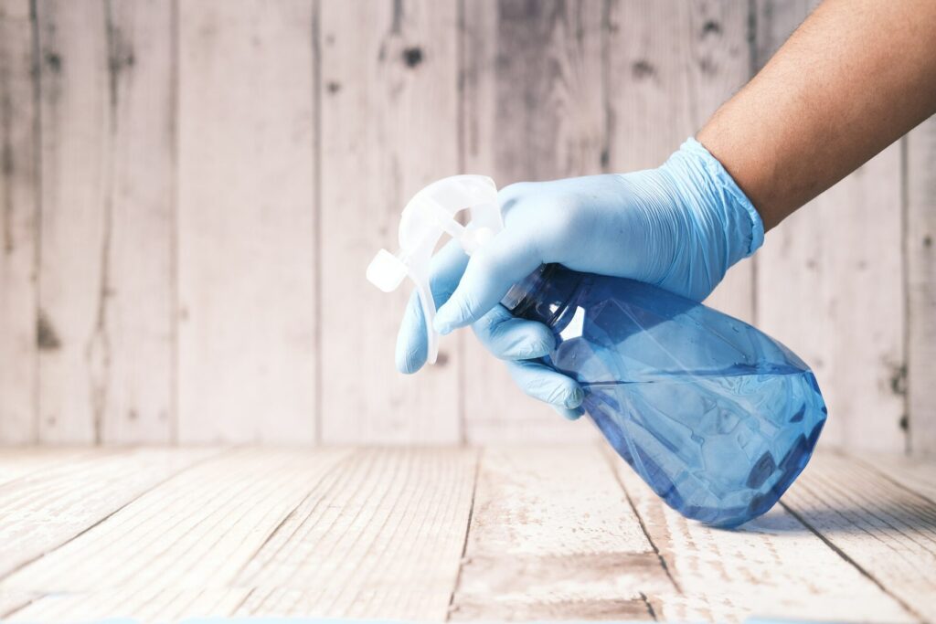 Hand met handschoen en sproeiflacon